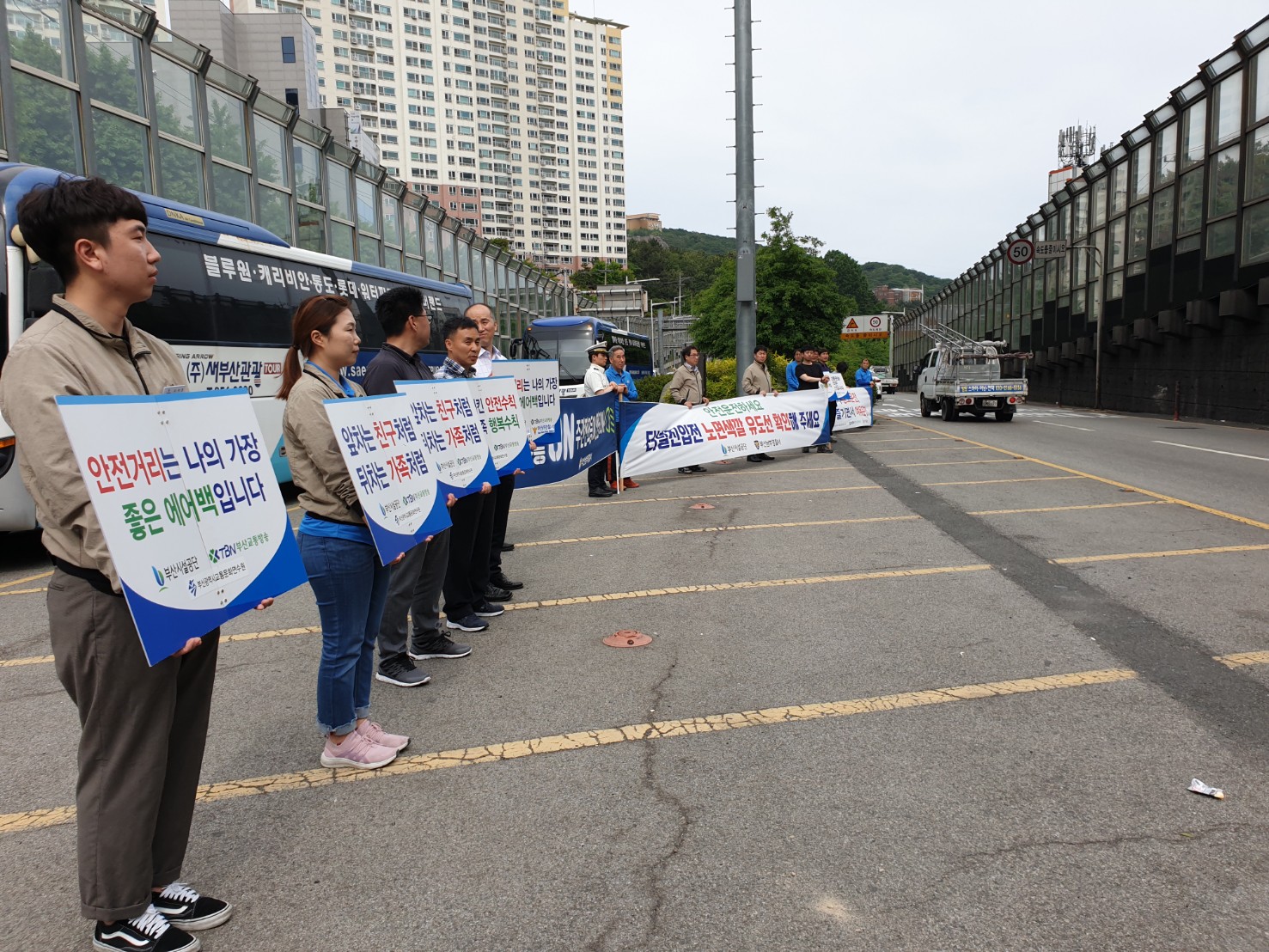 황련터널 전포방면 입구에서 교통문화정착 위한 캠페인 피켓과 현수막을 들고 사람들이 서 있다.(측면사진)